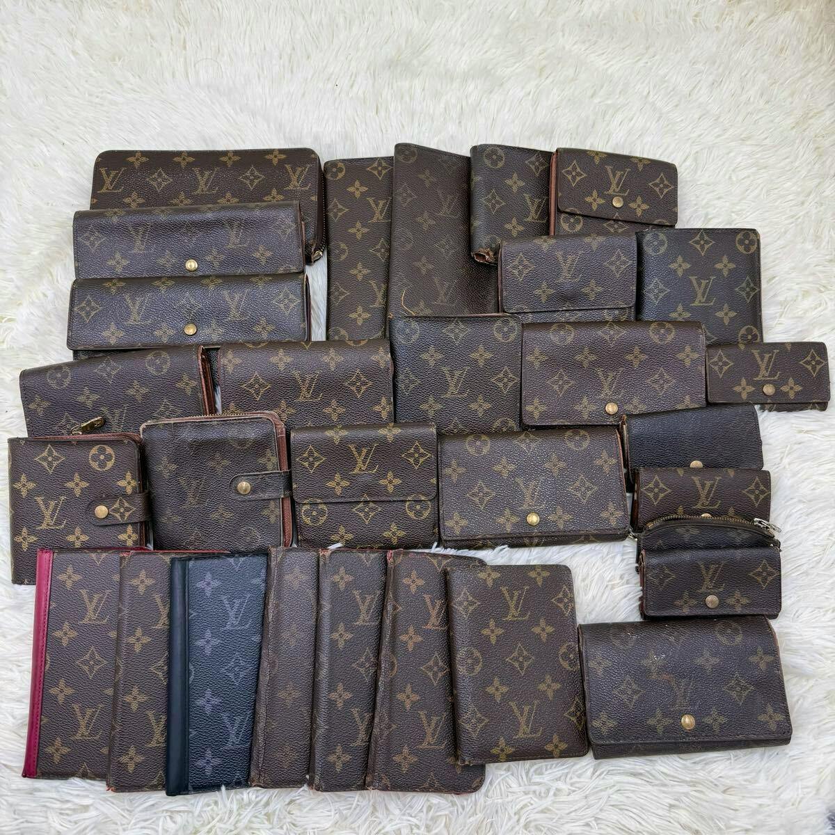 Many Louis Vuitton monogram canvas wallets and small accessories arranged on a white fuzzy surface.
