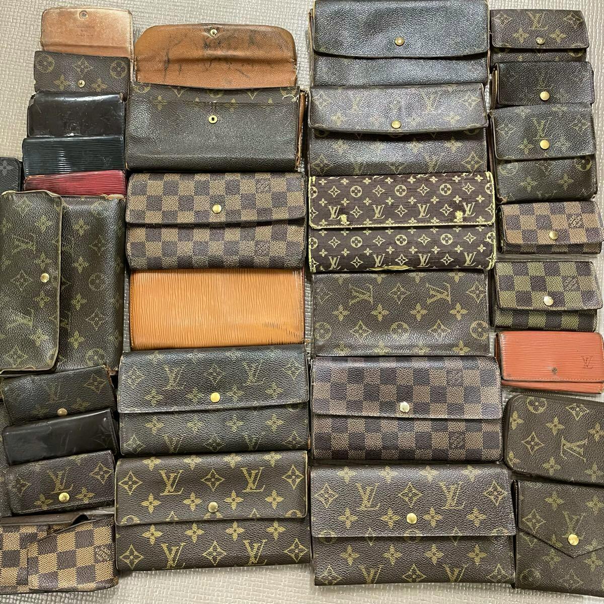 A laid-out assortment of Louis Vuitton wallets and small leather goods showing monogram and Damier patterns.