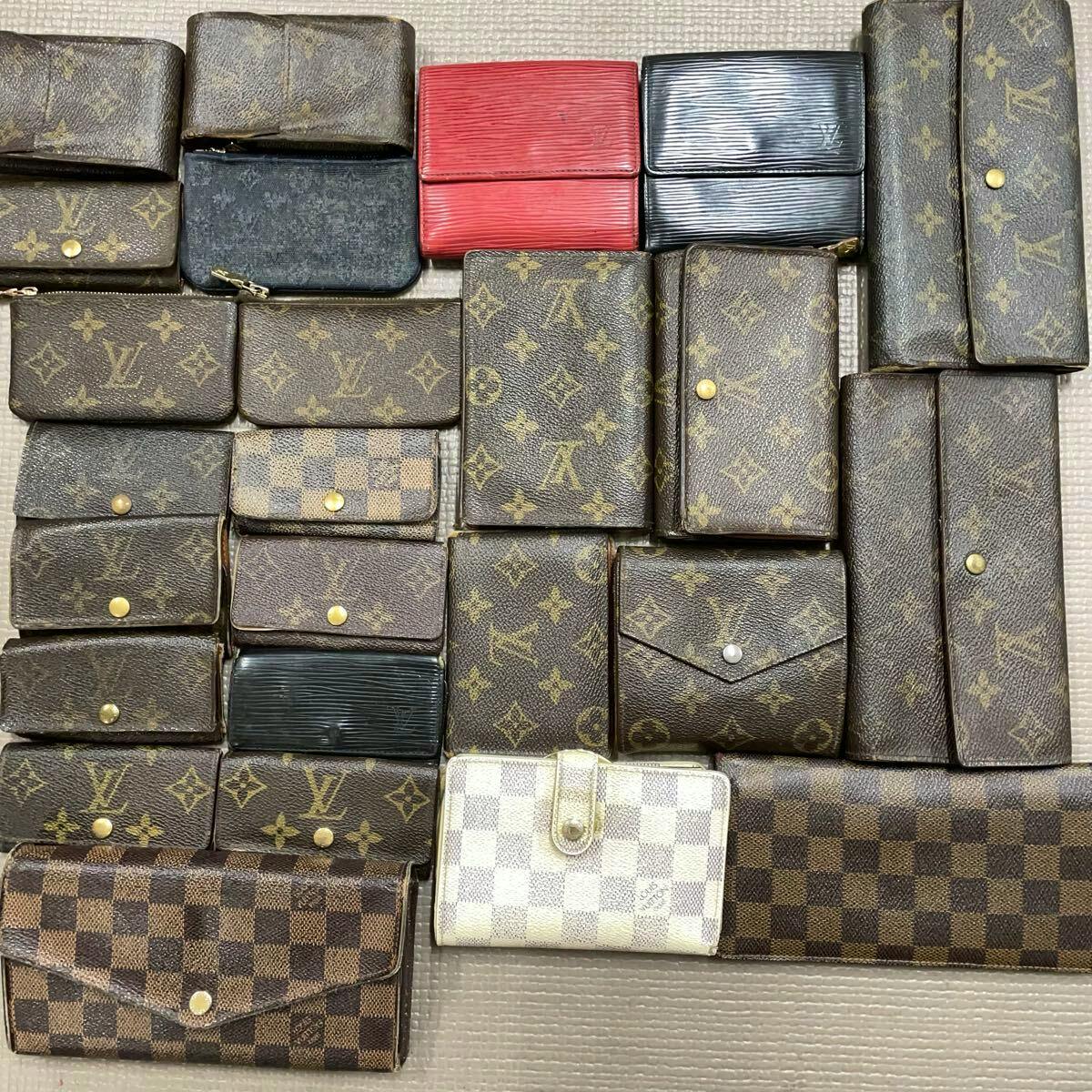 Top-down photo of multiple Louis Vuitton wallets and small leather goods arranged in a grid, showing monogram and Damier canvases.