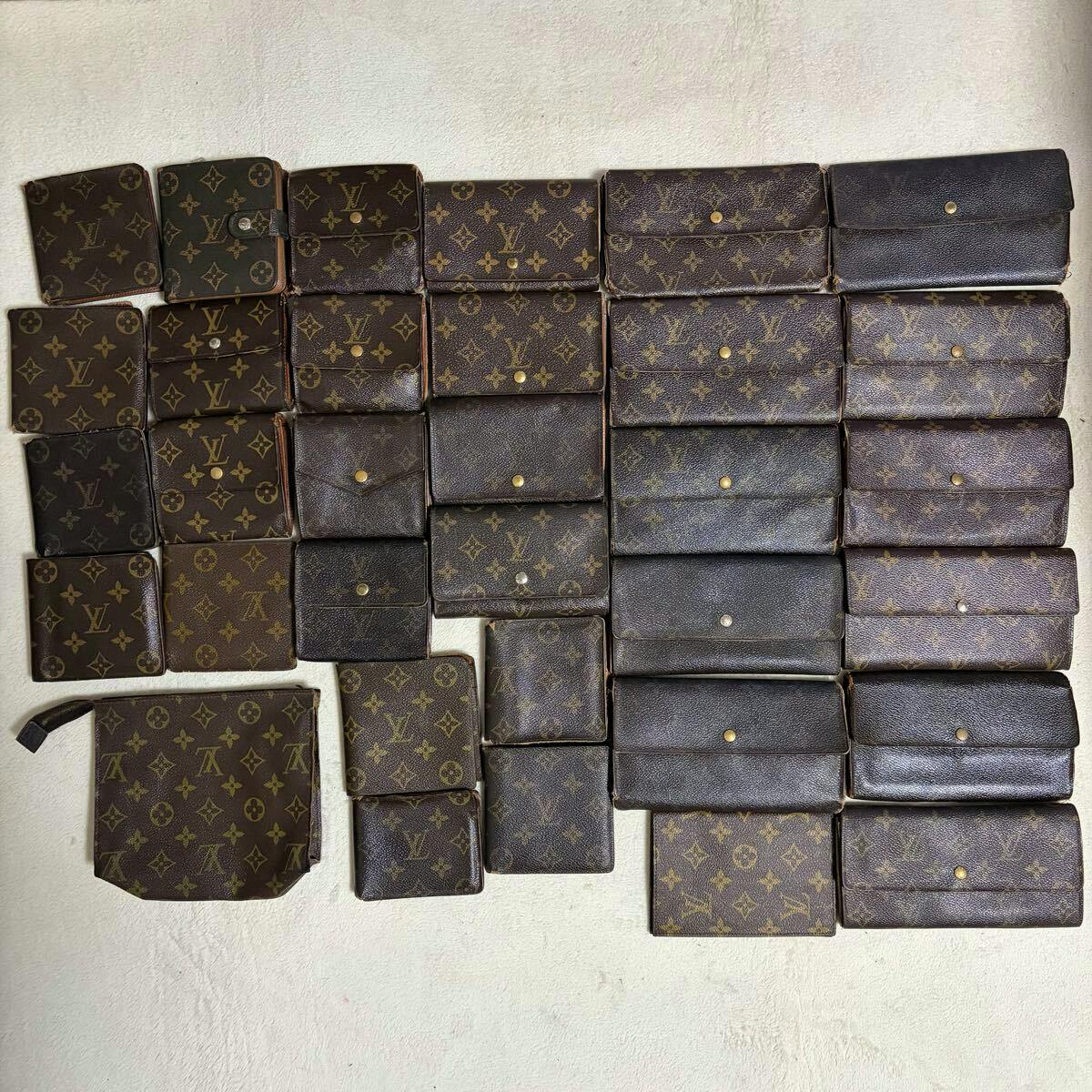 Multiple Louis Vuitton monogram wallets and small pouches arranged on a light background.