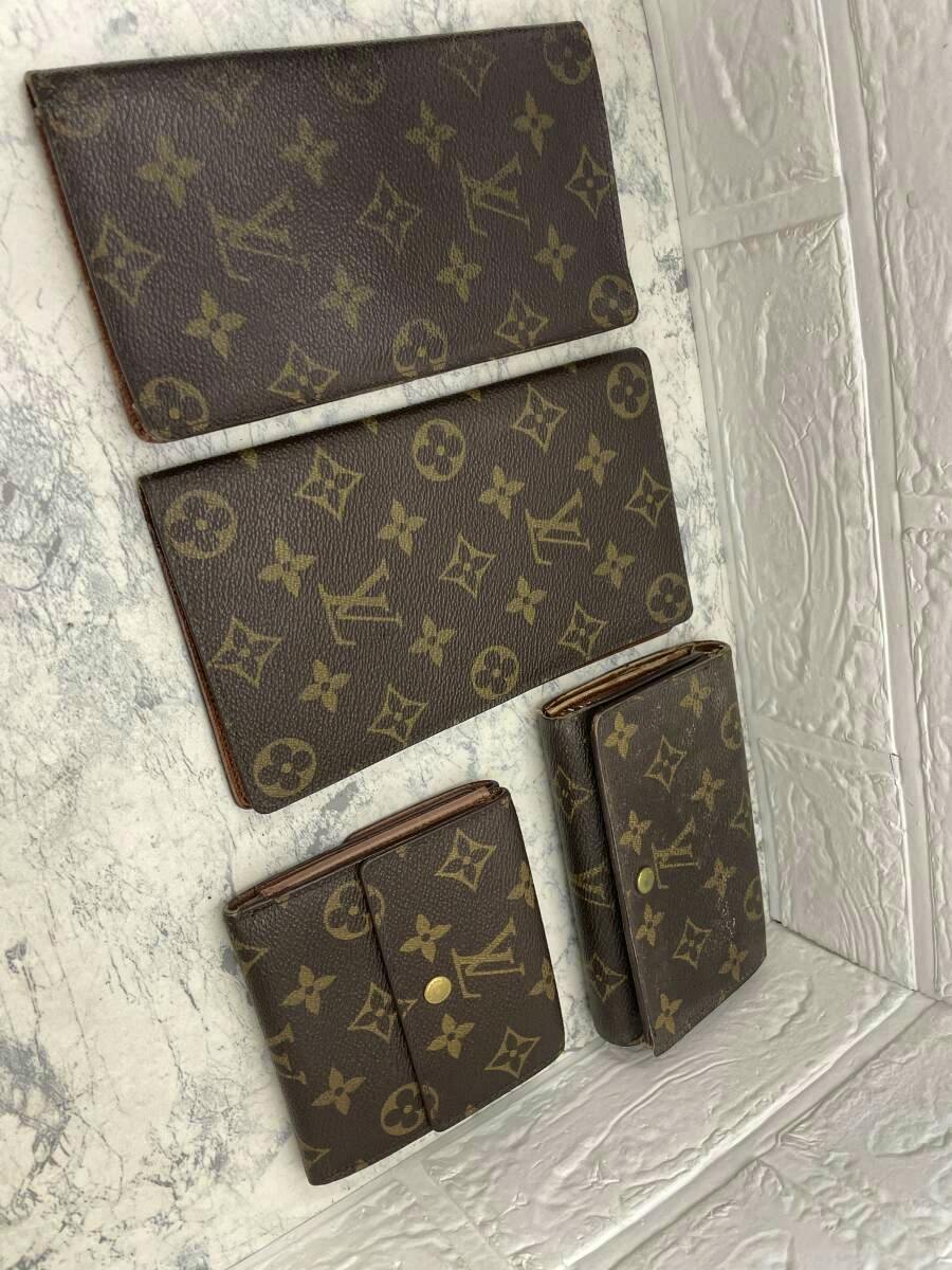 Four Louis Vuitton monogram canvas wallets displayed together on a light textured surface.
