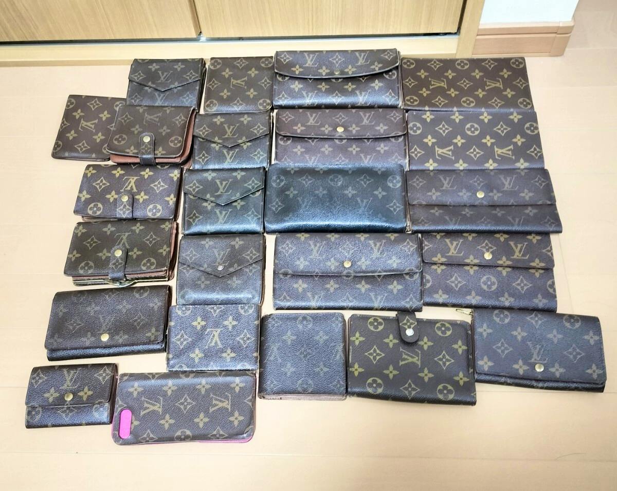 Multiple Louis Vuitton monogram wallets and small pouches arranged flat on a light-colored floor.