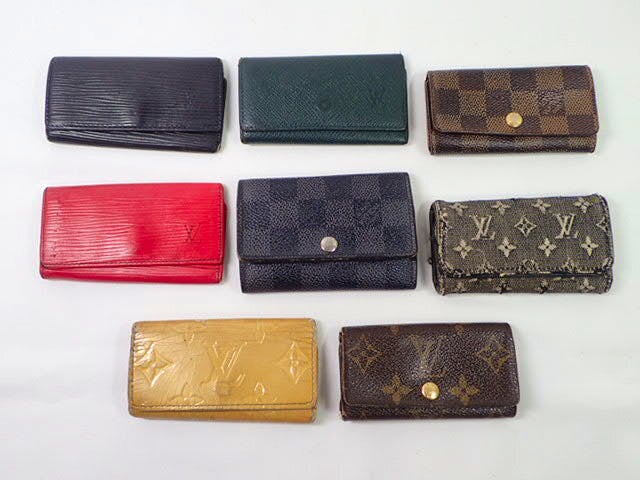 Eight Louis Vuitton key cases in various materials and colors arranged on a white background.