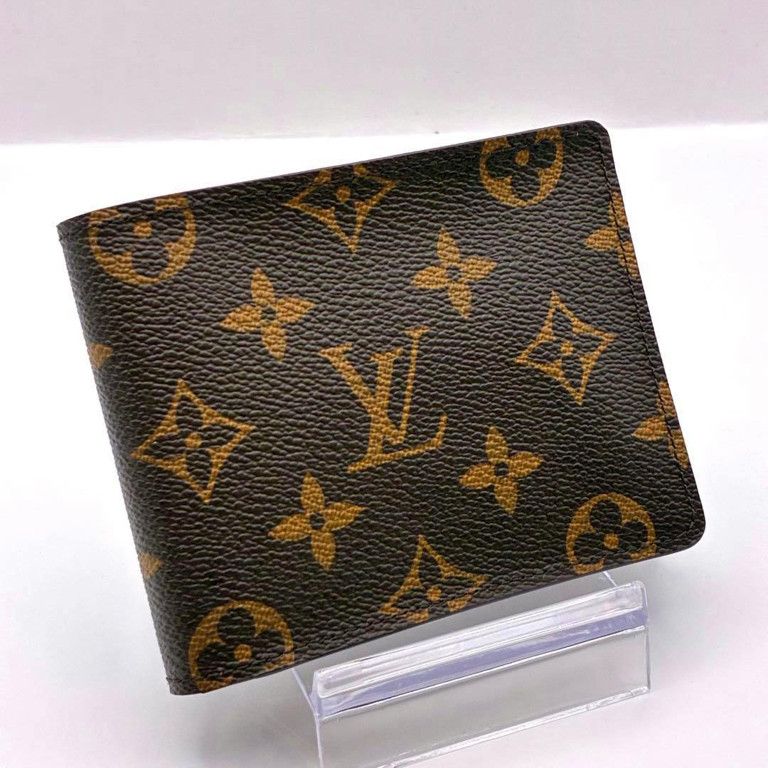 Louis Vuitton monogram bi-fold wallet displayed folded on a clear plastic stand.