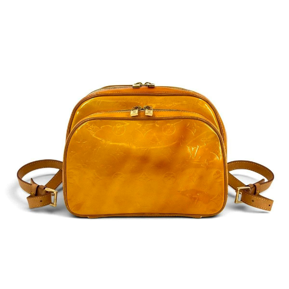 Yellow Louis Vuitton Monogram Vernis patent leather backpack with double zip compartments and leather straps on a white background.