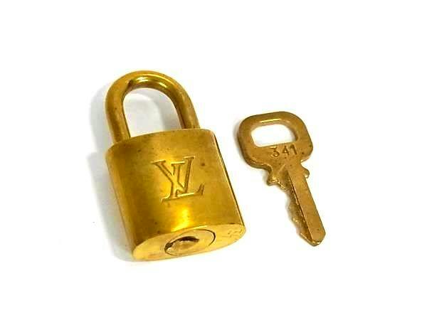 Gold-colored Louis Vuitton padlock with LV logo and matching key marked "341" on a white background.