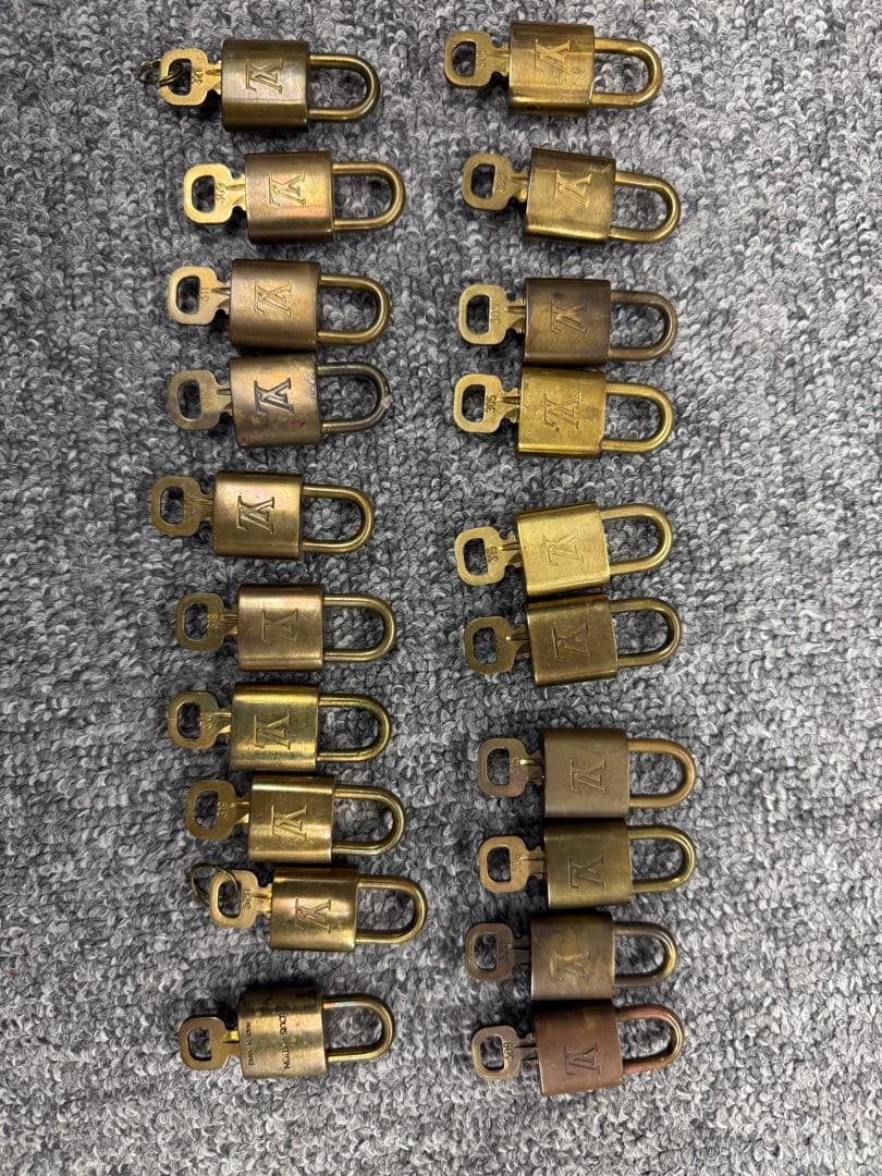 Multiple Louis Vuitton padlocks arranged in two columns on a carpeted surface.