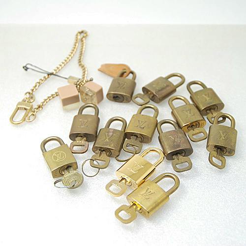 Multiple Louis Vuitton padlocks with keys and a wallet chain displayed on a white surface.