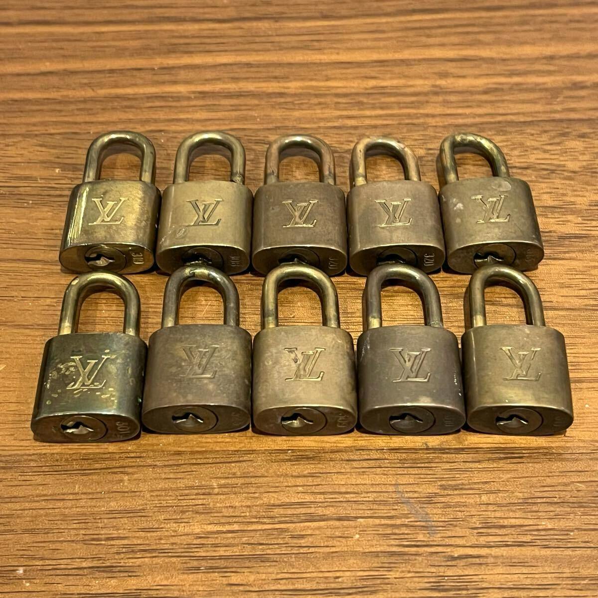 Ten Louis Vuitton padlocks (no keys) arranged in two rows on a wooden surface, each showing the LV logo.