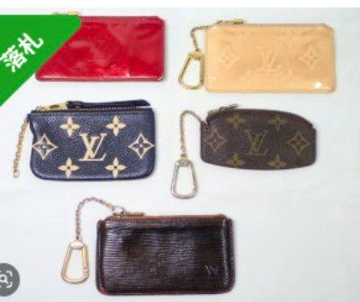 Five small Louis Vuitton key/coin pouches in various materials and colors arranged on a white background.