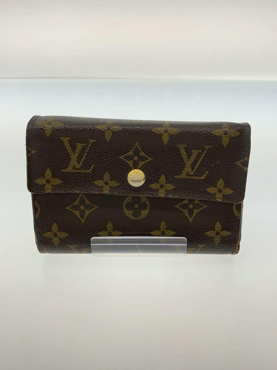 Front view of a Louis Vuitton monogram canvas wallet with a central snap button closure displayed on a clear stand.