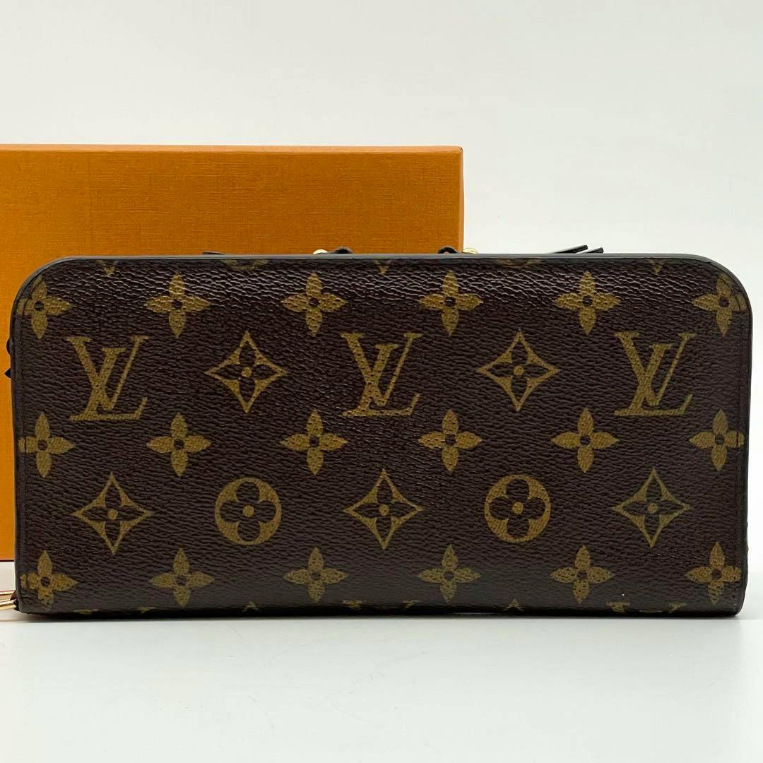 Front view of the Louis Vuitton monogram canvas wallet showing the LV monogram pattern with the orange Louis Vuitton box in the background.