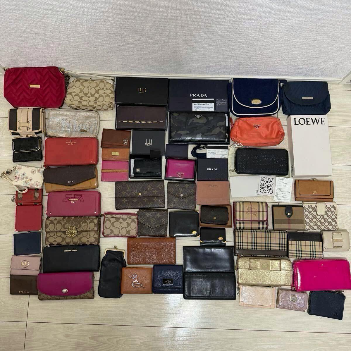 A large assortment of wallets, small pouches, and boxed items from various brands arranged on a floor as a bulk set.