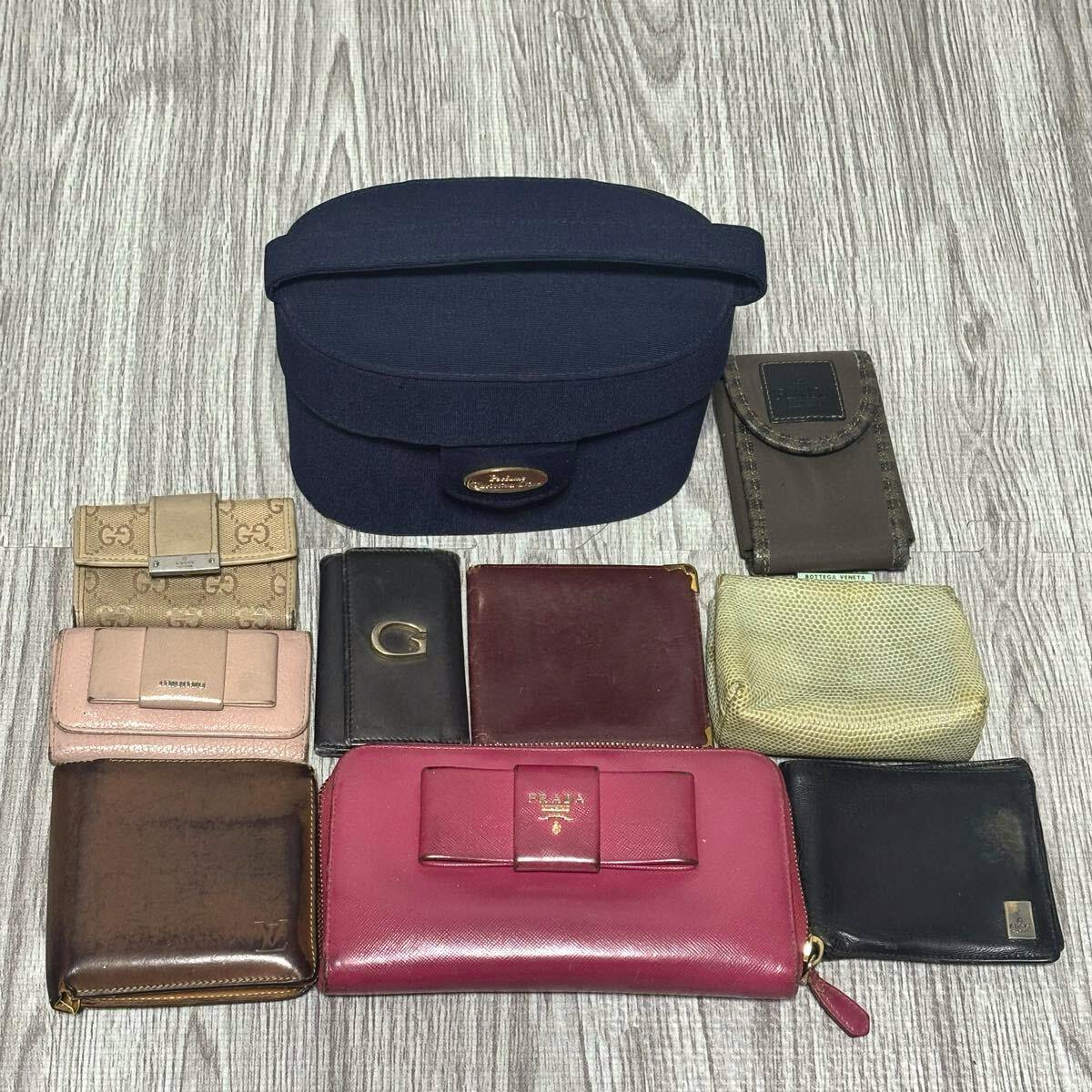 Ten assorted wallets, key cases, and pouches arranged on a wood floor with a navy case at the top.