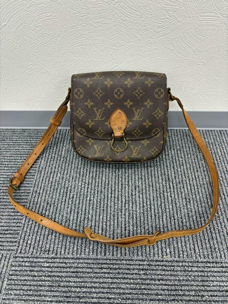 Front view of the LOUIS VUITTON Monogram shoulder bag (Sankuru PM M51244) with brown leather strap laid out on a carpeted floor against a textured wall.