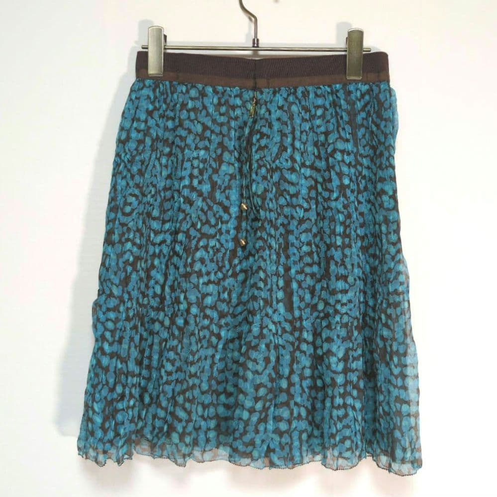 Teal and black tiered silk women's skirt (Louis Vuitton, size 38) hanging on a hanger against a white background.