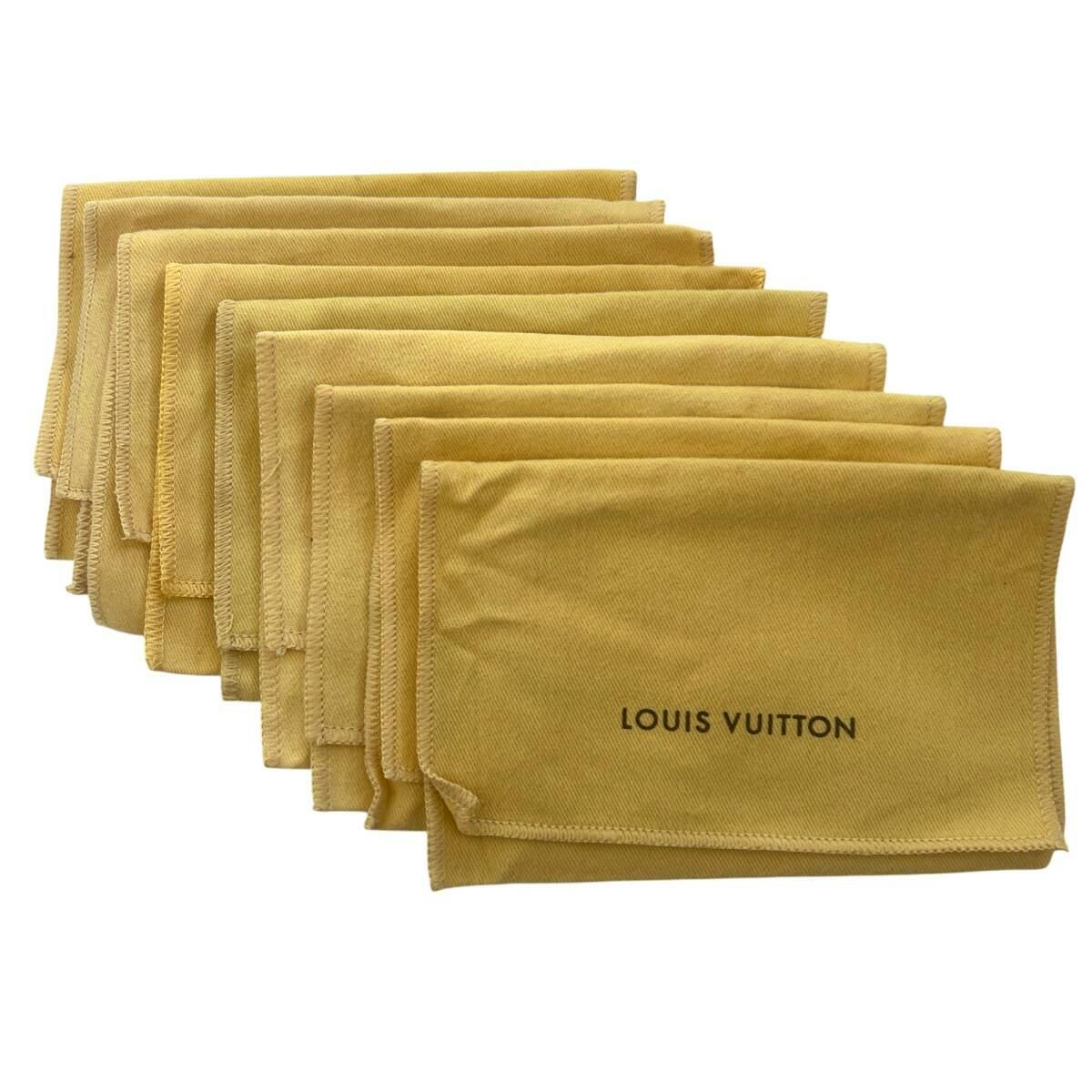 A stack of beige Louis Vuitton dust bags with "LOUIS VUITTON" printed on the front.