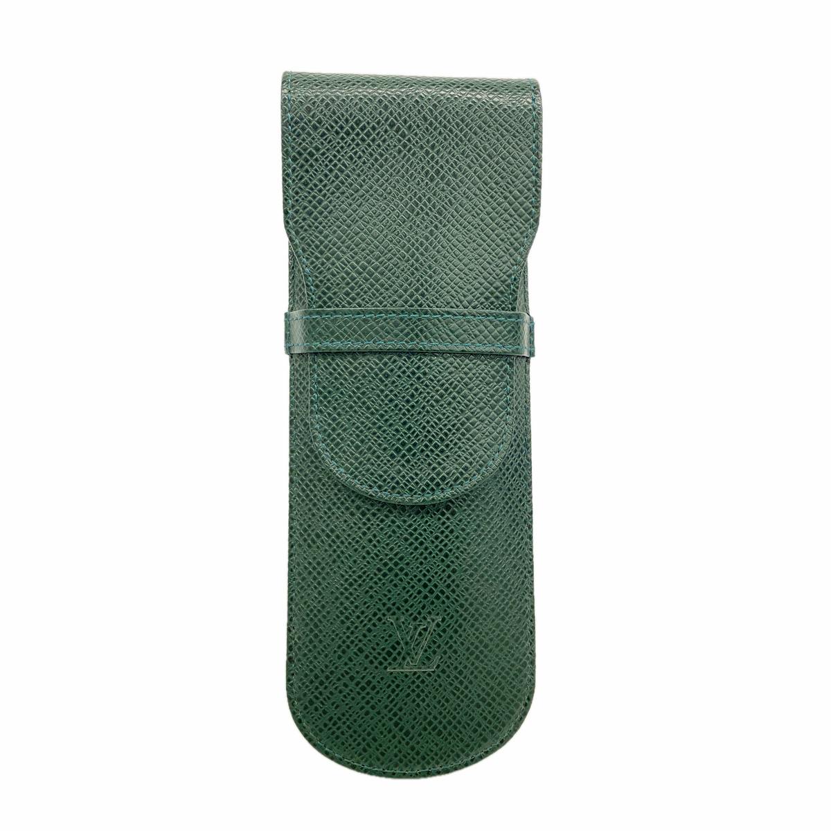 Green Louis Vuitton pen case in Taiga leather shown front-facing with flap closed and embossed LV logo.