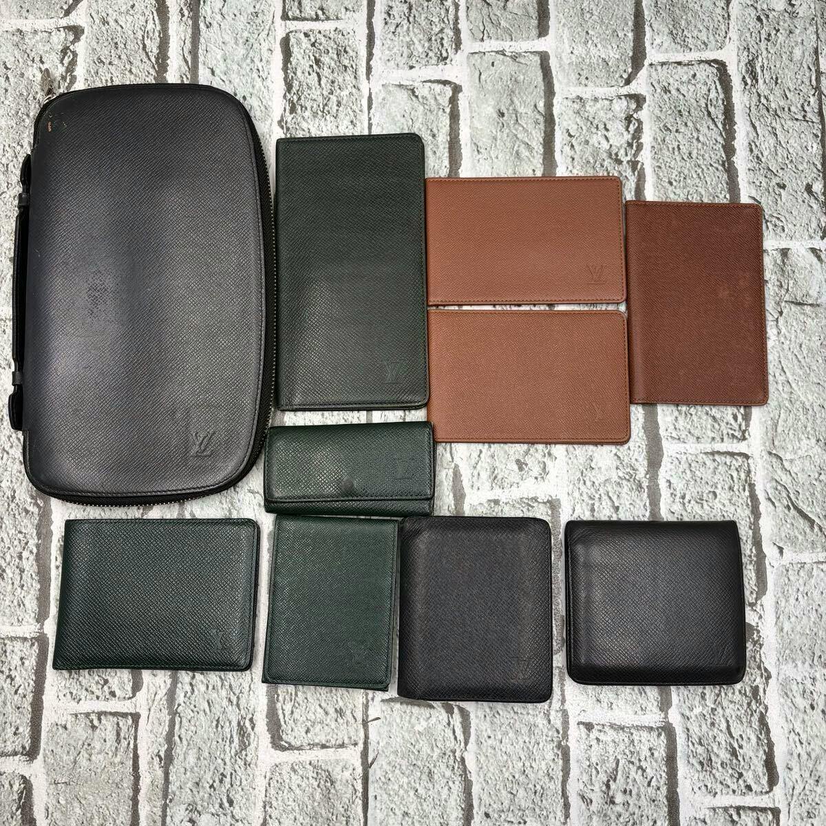 Ten Louis Vuitton cow leather wallets and small cases in various colors arranged on a light brick-patterned surface.