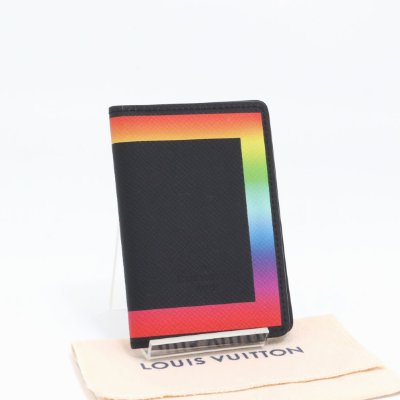 Front view of a black Louis Vuitton card case with a rainbow border displayed on a Louis Vuitton cloth.