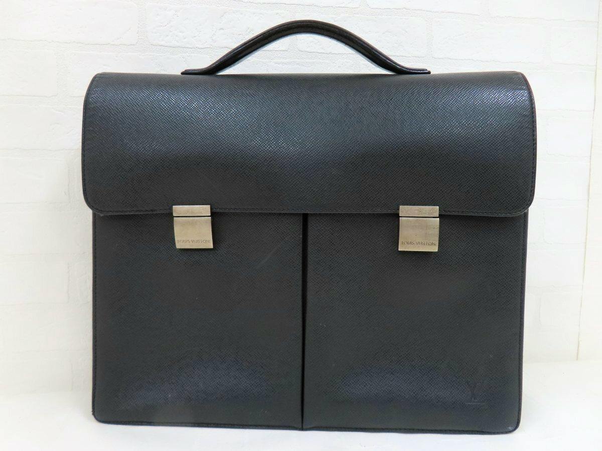 Front view of the black Louis Vuitton men's leather business bag with a top handle, flap closure, and two silver-tone clasps.