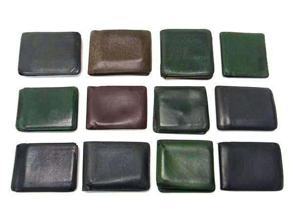 Twelve assorted LOUIS VUITTON Taiga leather wallets arranged in rows on a white background.