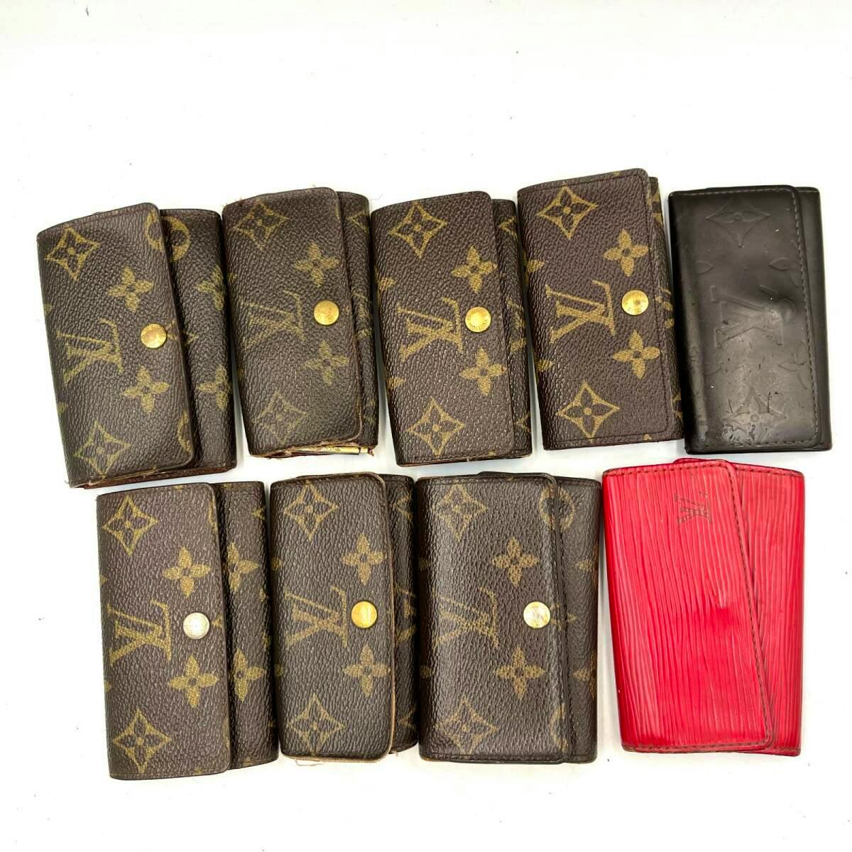 Nine Louis Vuitton key cases in monogram canvas and leather arranged on a white background.