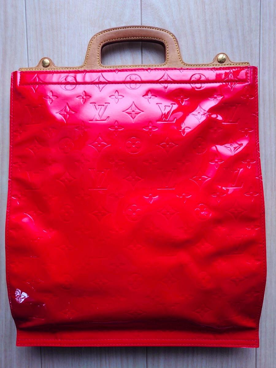 Front view of a red Louis Vuitton Vernis Stanton handbag showing the embossed monogram pattern and tan leather top handles.