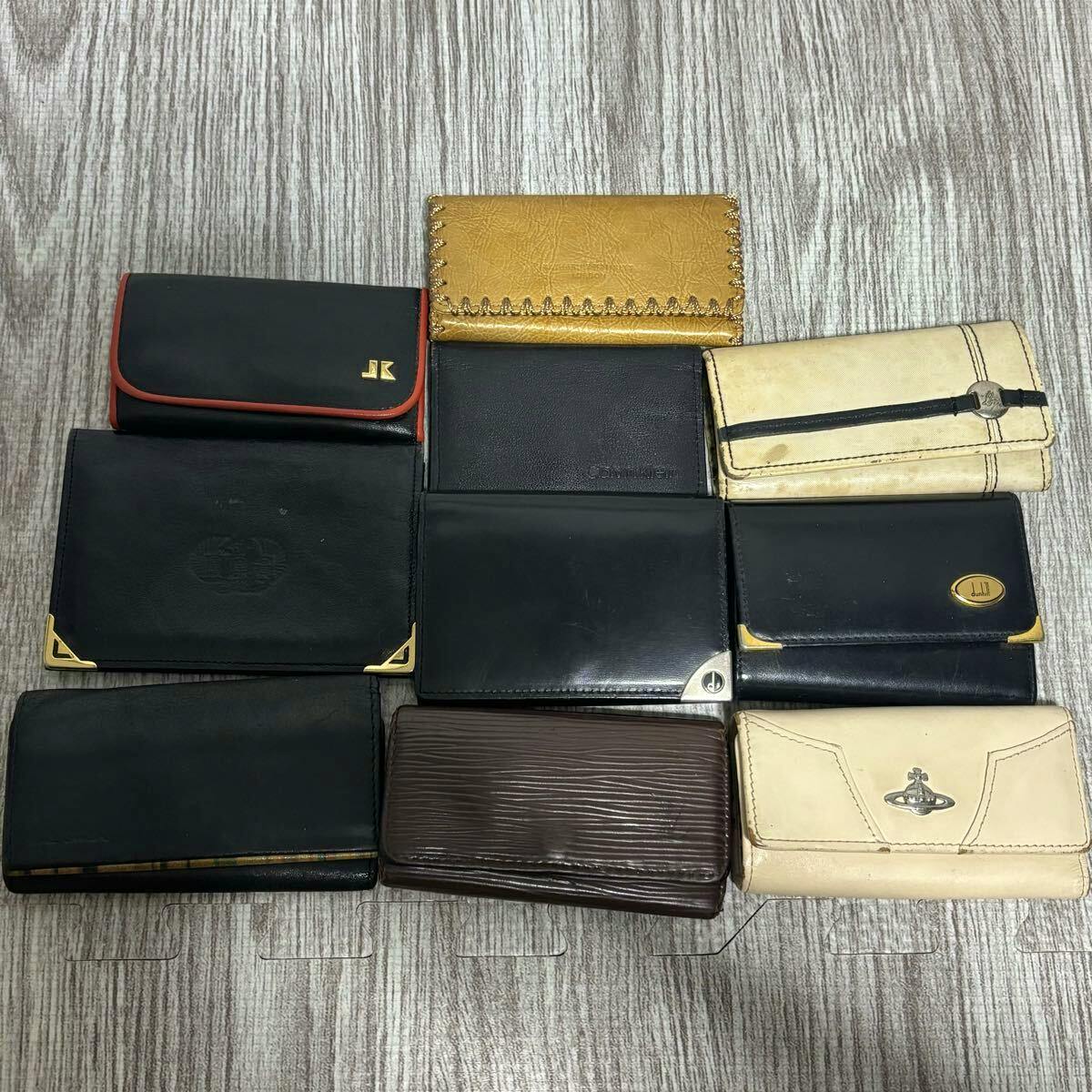 Ten assorted wallets and small cases arranged on a wood-textured surface, showing different colors and visible wear.