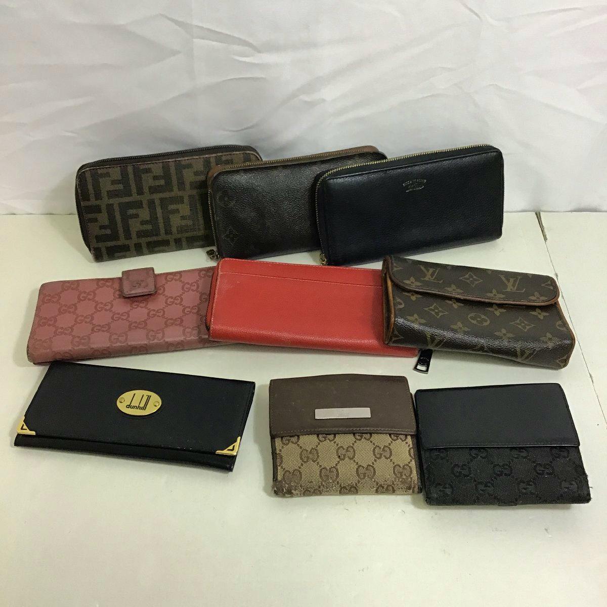 Several used wallets, including monogram and leather styles, arranged on a white surface.