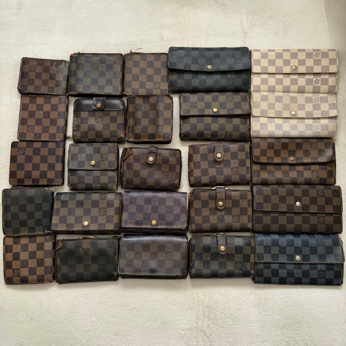 Multiple wallets and small coin/card cases with Damier checkered canvas patterns arranged in rows on a light surface.