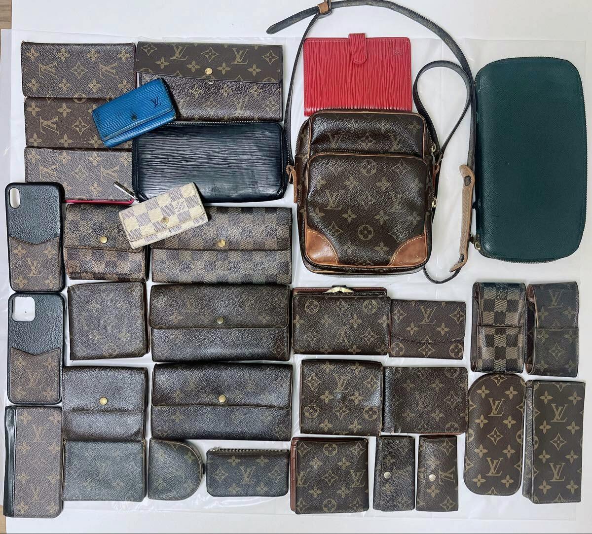Overhead photo of a large assortment of Louis Vuitton wallets and small leather goods in monogram, Damier, and Epi patterns arranged on a white background.