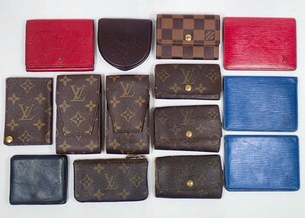Fourteen Louis Vuitton small leather goods (wallets, coin cases, key cases) laid out flat on a white background.