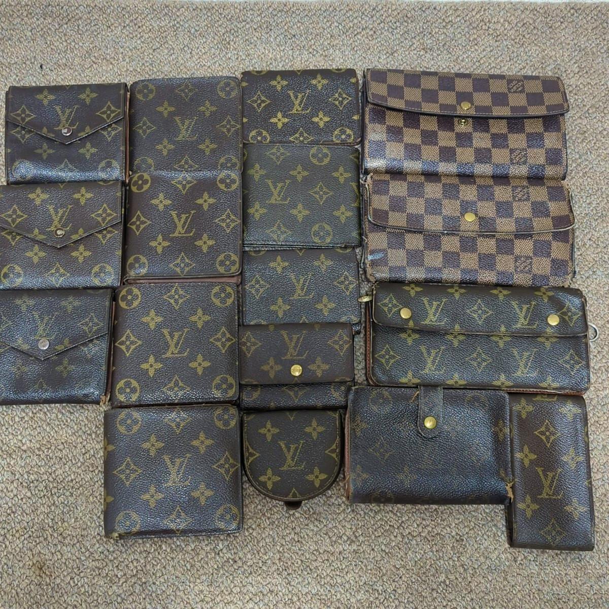 Multiple Louis Vuitton wallets and small leather accessories in monogram and Damier patterns arranged on a carpet.