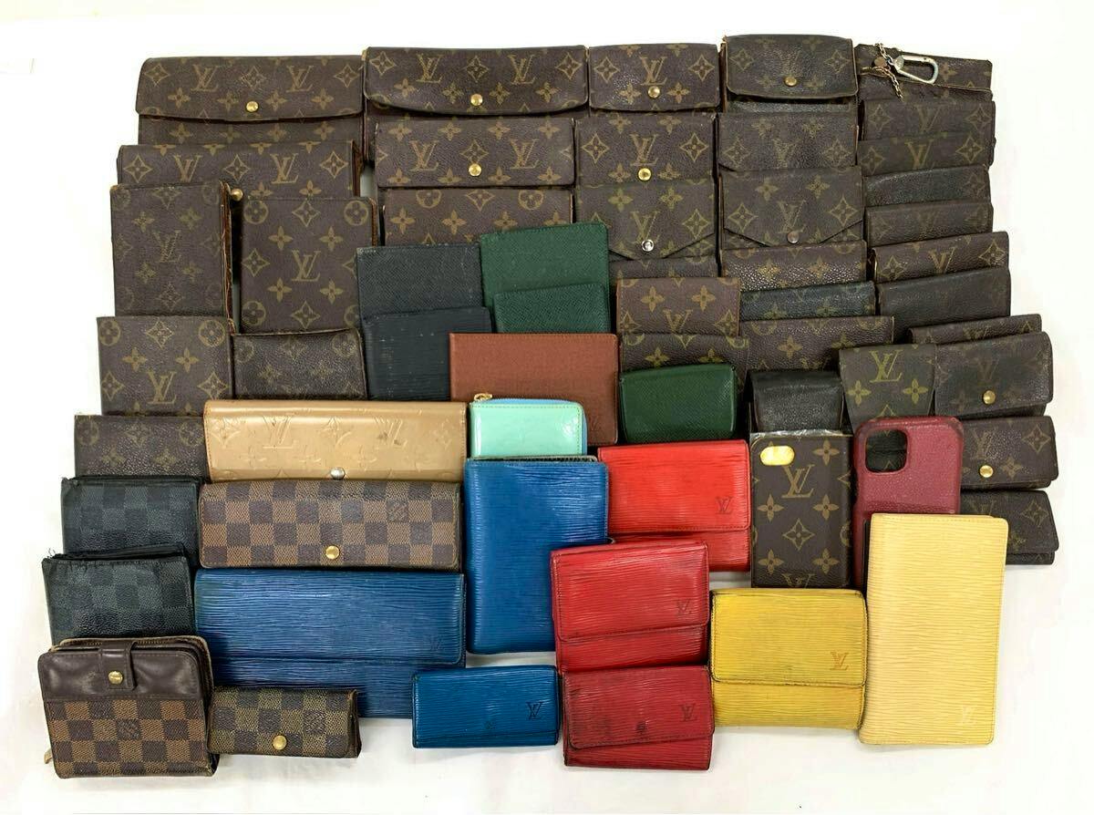 Multiple Louis Vuitton wallets in monogram, Damier, and colored leather arranged on a white background.