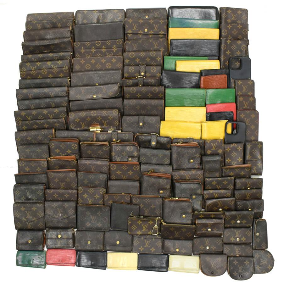 A large assortment of Louis Vuitton wallets and small leather goods arranged on a white background.