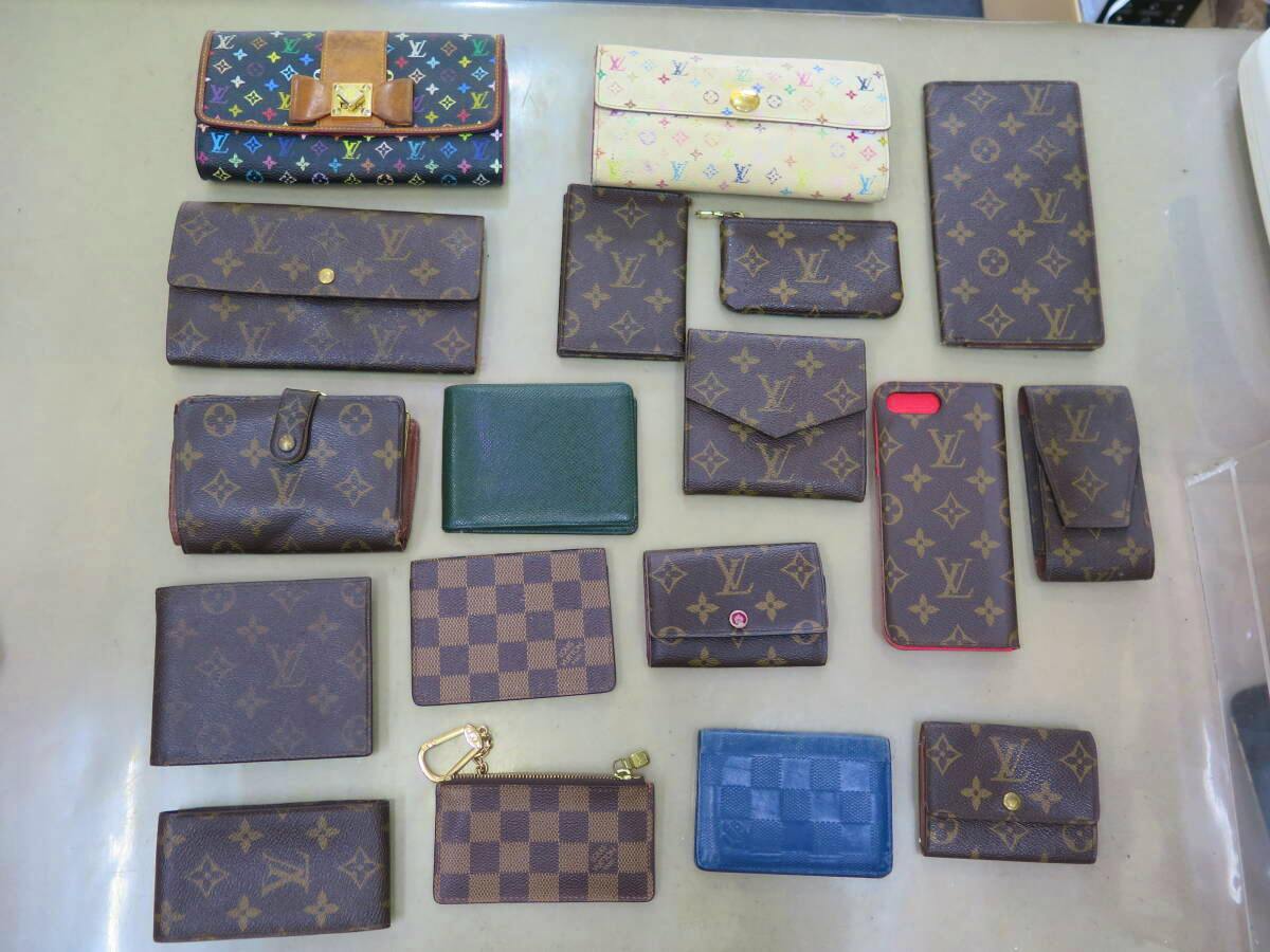 Overhead photo of multiple Louis Vuitton wallets and small leather goods arranged on a flat surface.