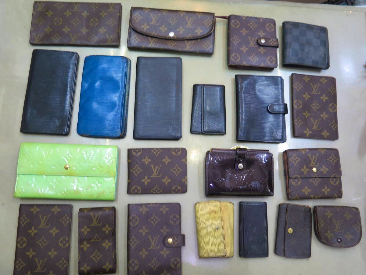 Several Louis Vuitton wallets and small accessories arranged in a grid on a flat surface.