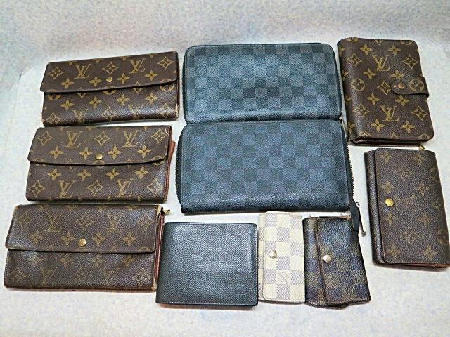 A collection of Louis Vuitton wallets and key cases in various monogram and Damier patterns arranged on a flat surface.