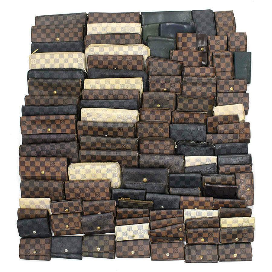 Many Louis Vuitton wallets and small leather goods in various canvas patterns arranged in rows on a white background.