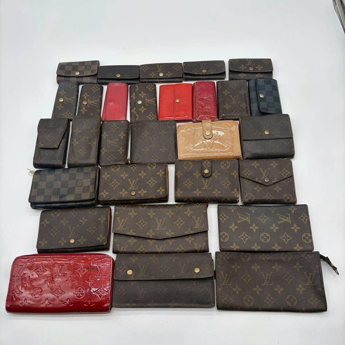 Top-down view of many Louis Vuitton wallets and small accessories arranged on a white background.