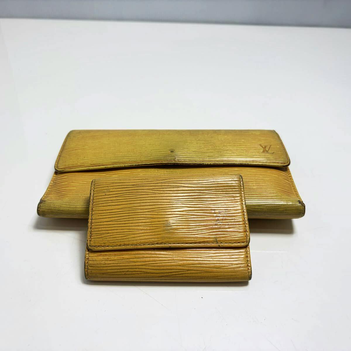Yellow Louis Vuitton leather long wallet and a smaller matching key case placed flat on a white background.