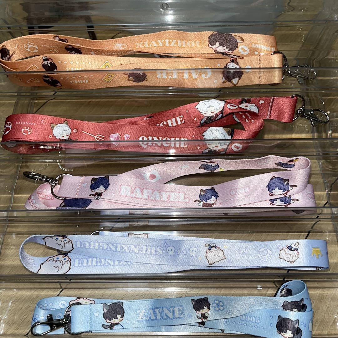 Five printed polypropylene neck straps with character designs and metal clips arranged in a display tray.