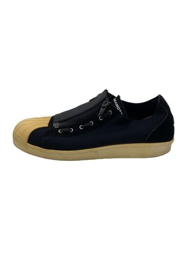 Side view of a black low-cut canvas sneaker with a beige rubber toe cap and beige sole.