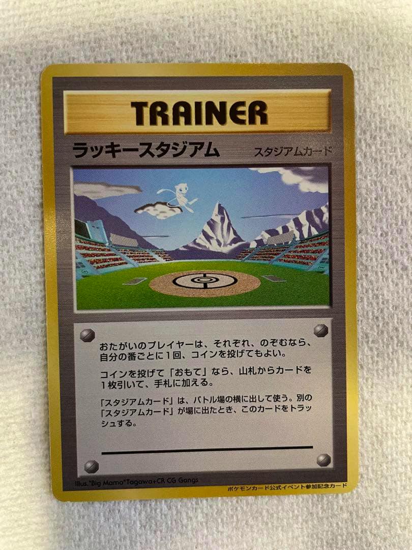 Front of a Japanese ラッキースタジアム (Lucky Stadium) Trainer Pokémon promo trading card lying on a white textured background.