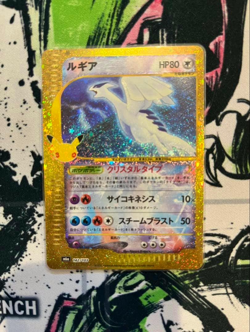 Front of a Lugia 30th anniversary trading card with holographic foil and gold border on a patterned surface.