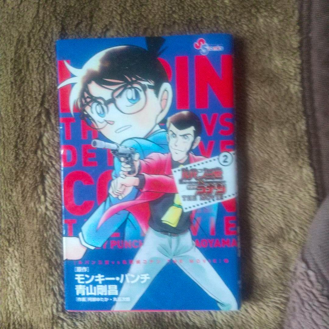Photograph of the comic book front cover 'ルパン三世VS名探偵コナン THE MOVIE 2' showing illustrated characters on a blue background, one pointing a handgun.