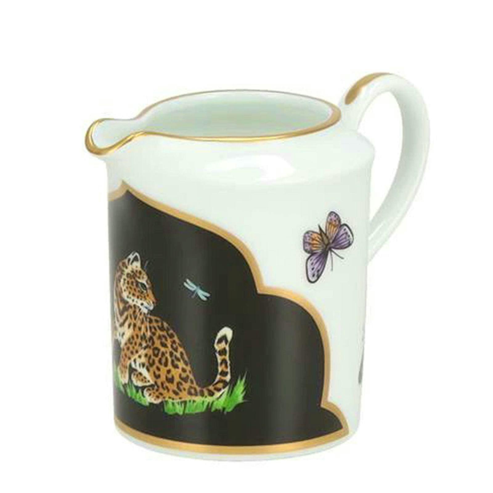 White ceramic creamer jug with a black panel showing a jaguar and a butterfly and gold trim.