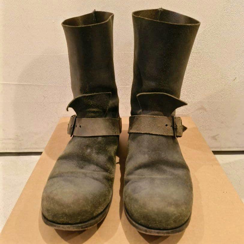 Front view of a pair of green m.a+ leather engineer boots, size 42, placed on a cardboard surface.