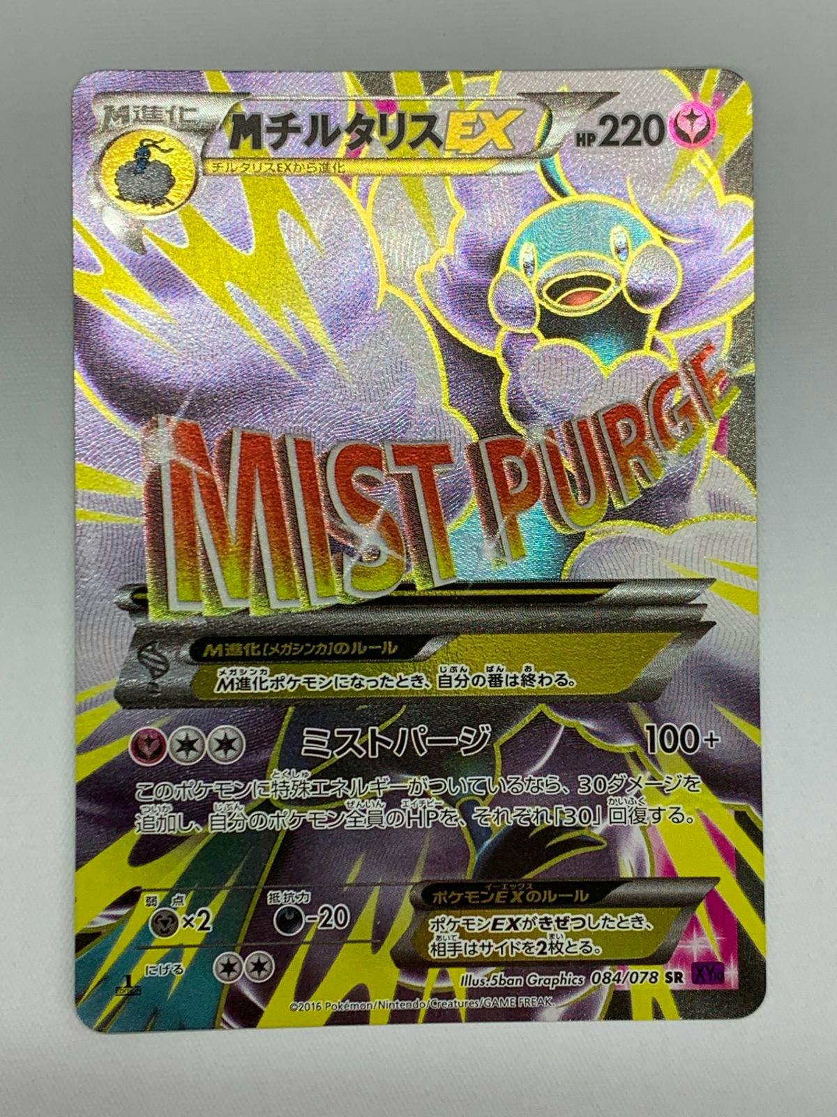 Photograph of the front of the trading card MチルタリスEX showing holographic artwork, large "MIST PURGE" text, and Japanese card text.